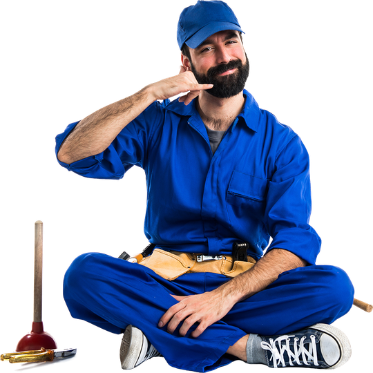Plumber in blue overalls gesturing a phone call, sitting with tools.