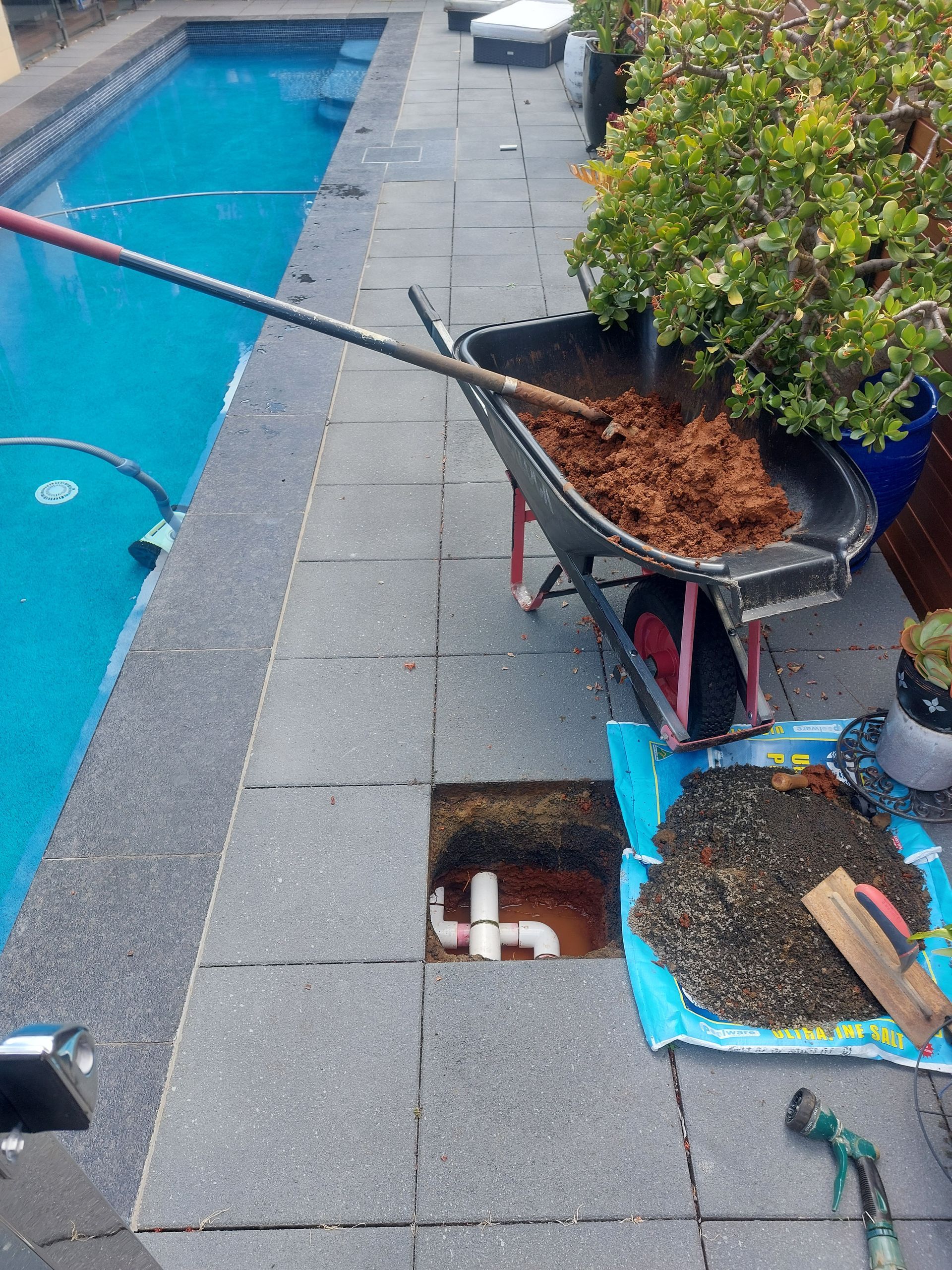 Man in Blue Uses a Pump to Drain Water From a Swimming Pool — Ballina Leak Detection & Swimming Pool Repairs in Byron Bay, NSW
