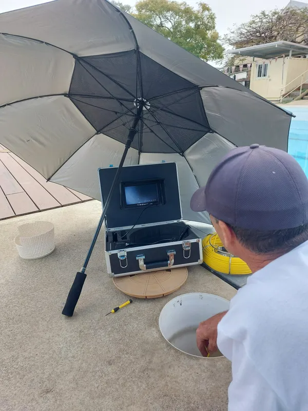 Man Using Equipment Near a Pool, Under an Umbrella — Ballina Leak Detection & Swimming Pool Repairs in Ballina, NSW