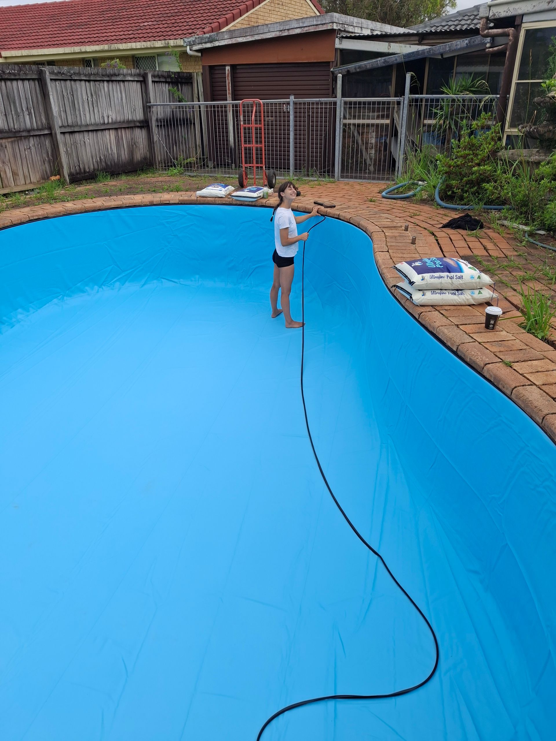 Person Cleaning a Blue Pool With a Long-handled Brush — Ballina Leak Detection & Swimming Pool Repairs in Ballina, NSW