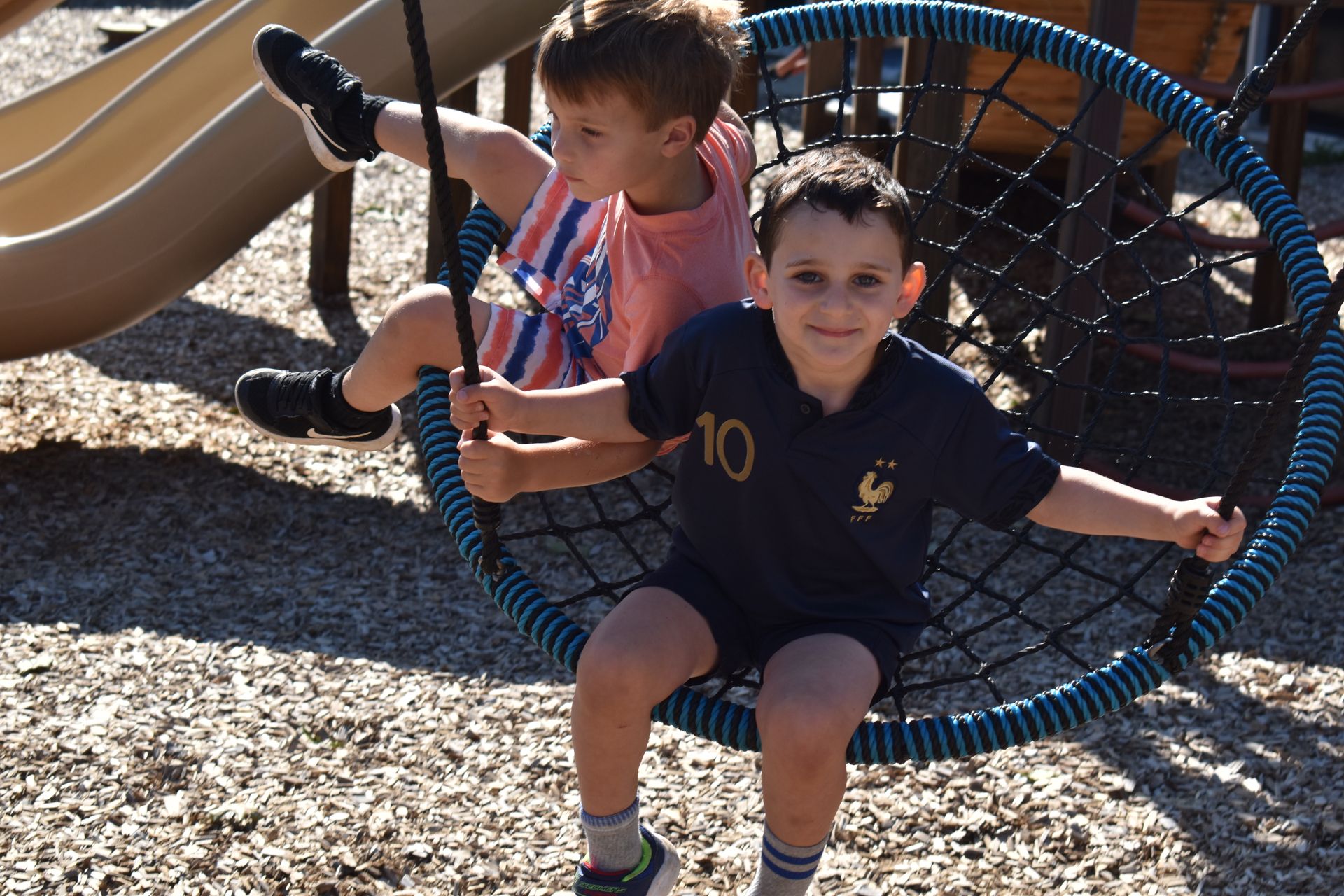 A boy wearing a number 10 shirt is sitting on a swing