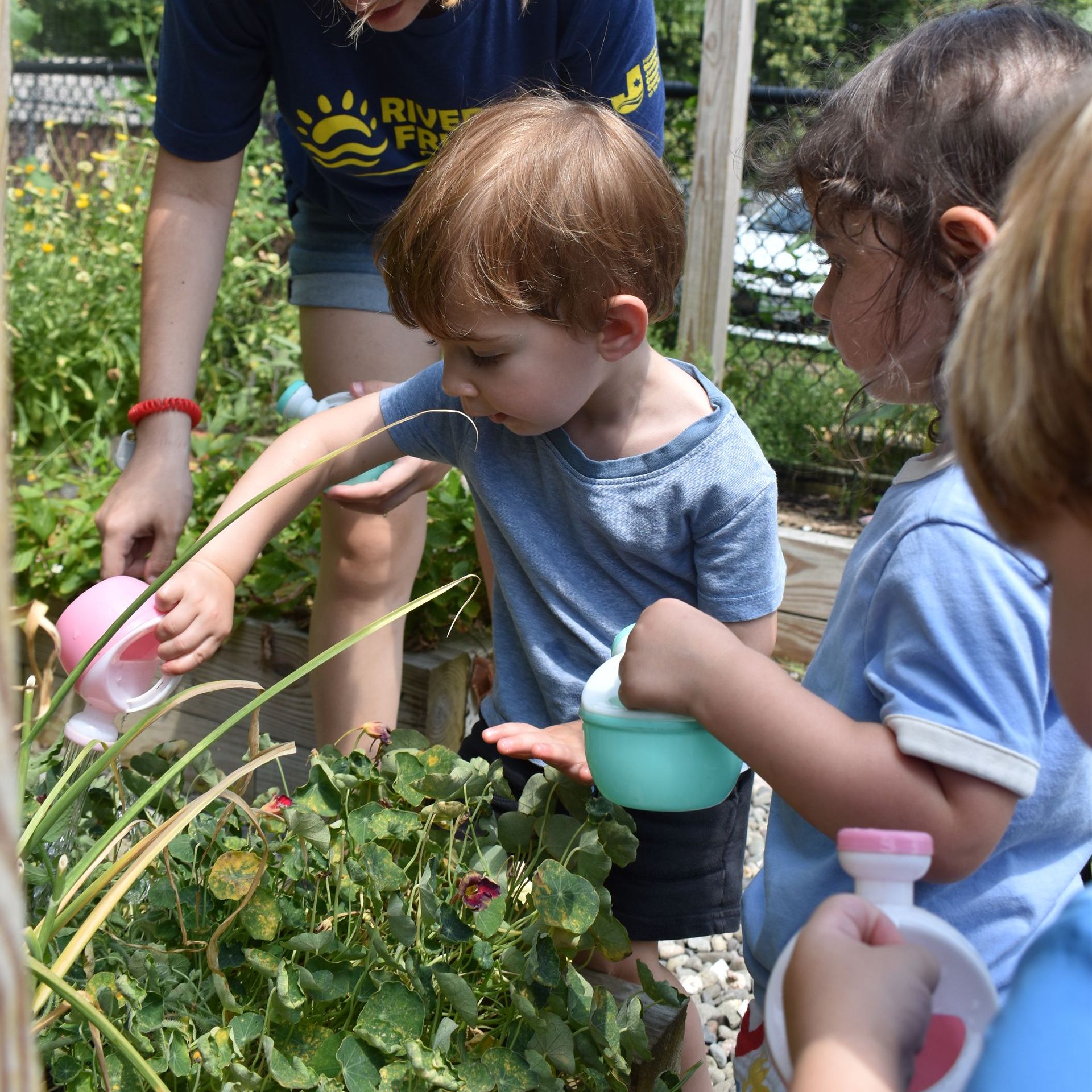 A woman in a river project shirt is watering a plant