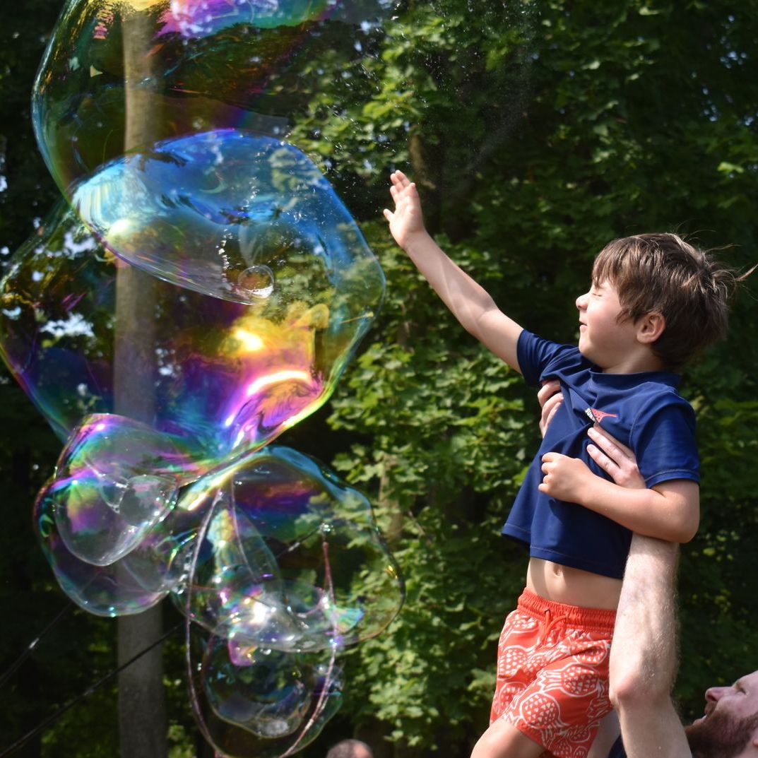 A little boy is reaching for a soap bubble