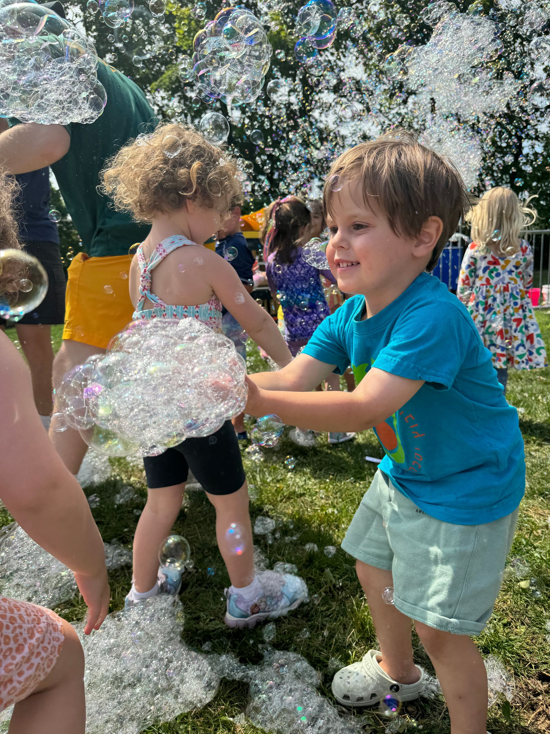 A group of children are playing with soap bubbles in the grass.