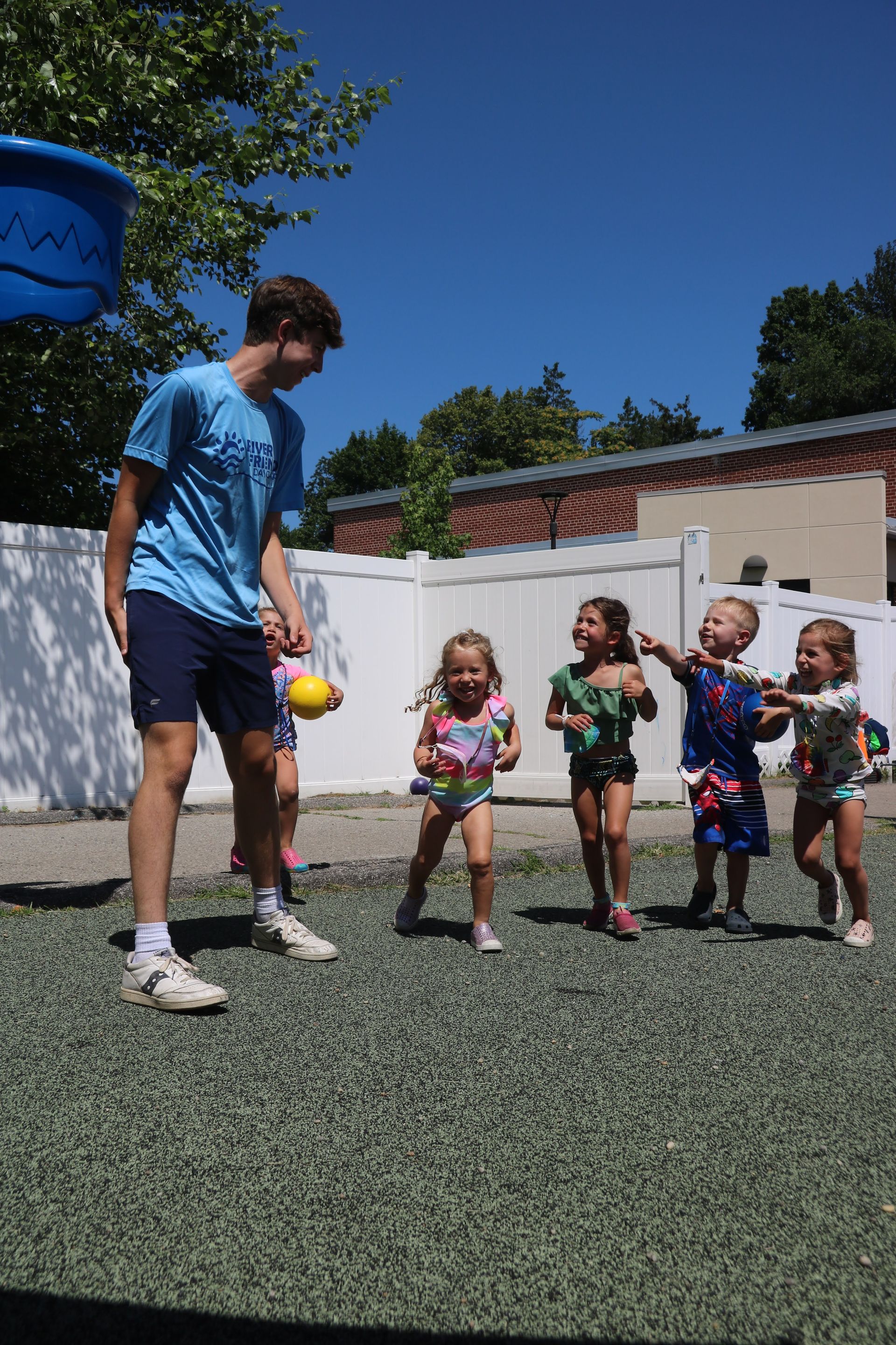 A group of children are playing with a man in a blue shirt.