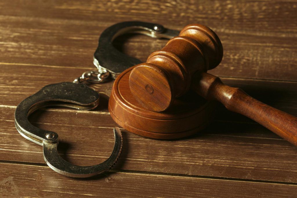 Handcuffs and gavel on a wooden surface, symbolizing law and justice.