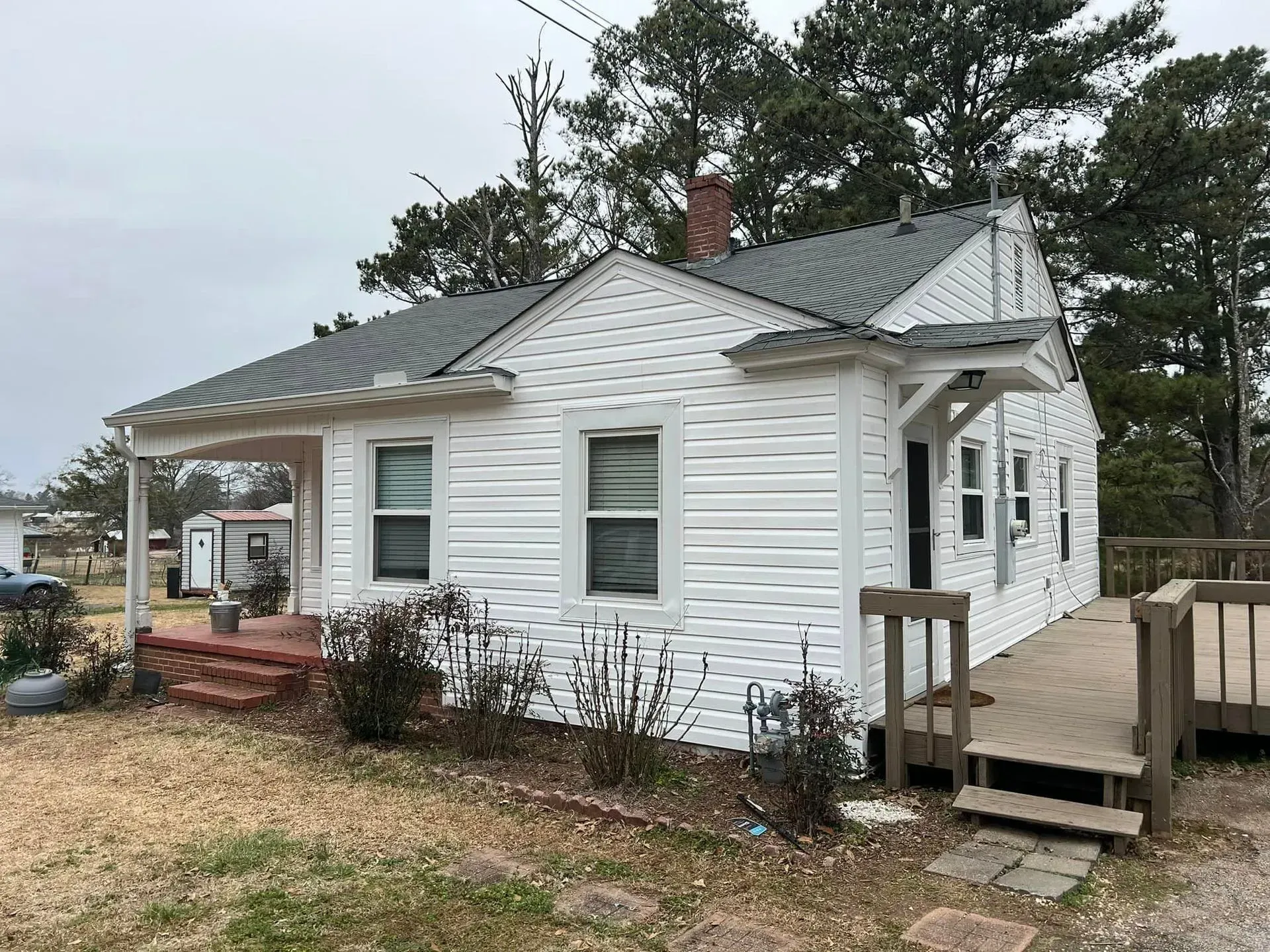 A small white house with a gray roof and a porch.