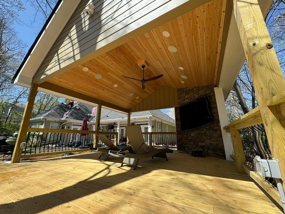 A wooden deck with a ceiling fan and a fireplace.