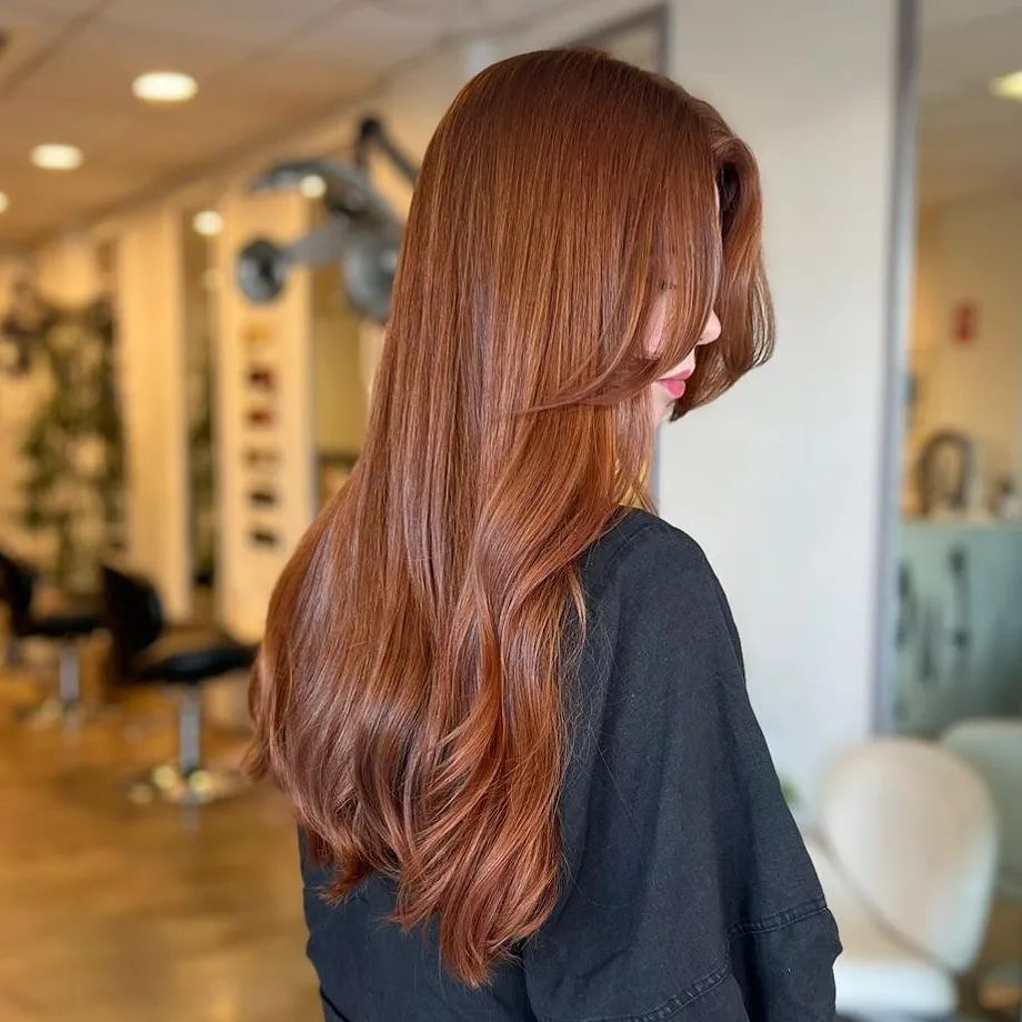 A Woman With Long Red Hair Is Wearing A Black Shirt — Fuse Hair & Beauty In Darwin City, NT
