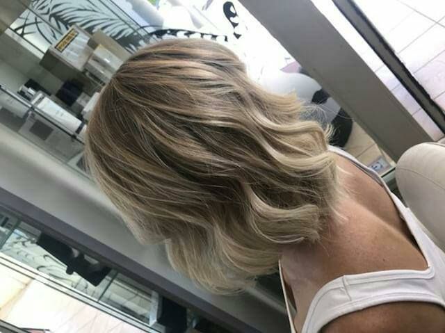A Woman With Blonde Hair Is Standing In Front Of A Mirror — Fuse Hair & Beauty In Darwin City, NT