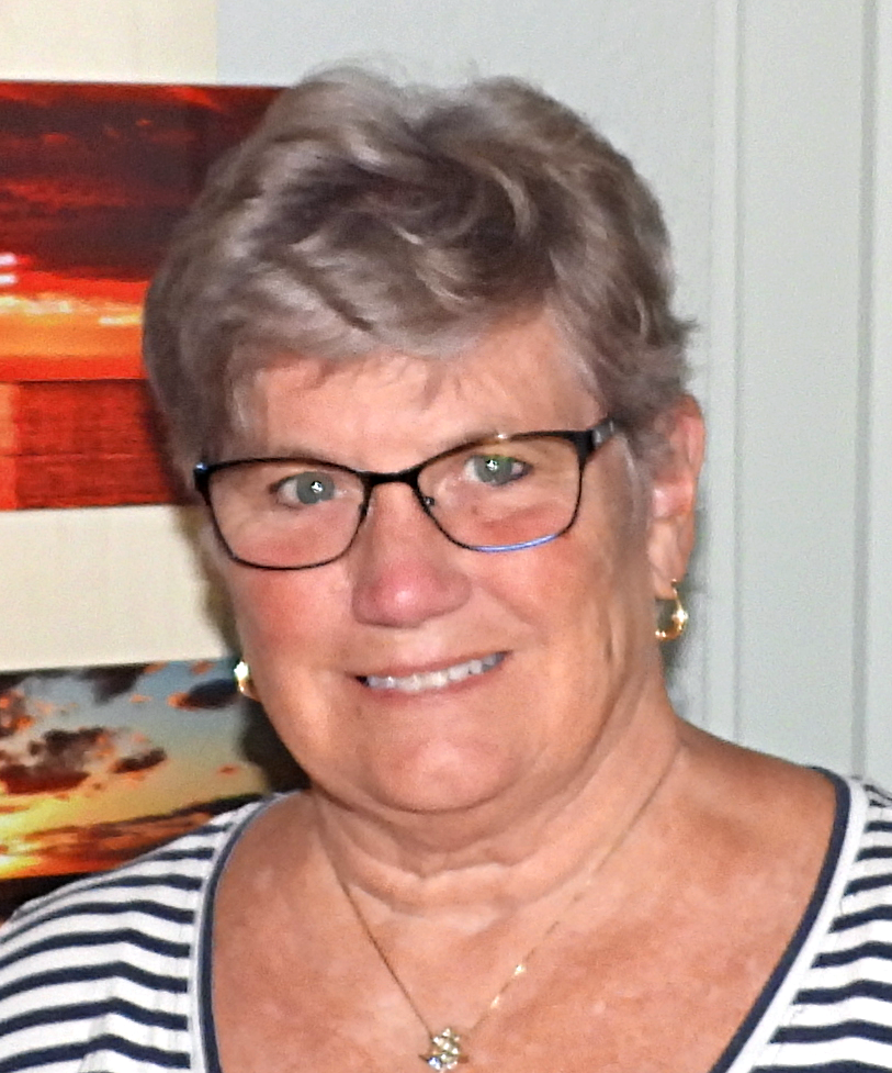 A woman wearing glasses and a black turtleneck smiles for the camera