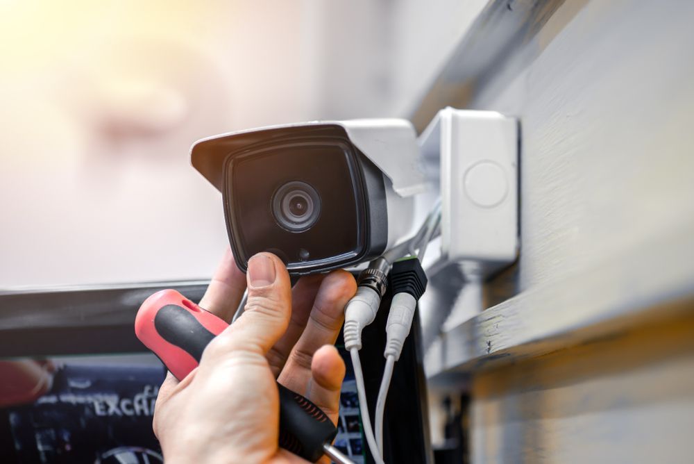 A Person is Fixing a Security Camera With a Screwdriver — Adept Security In Oak Flats, NSW