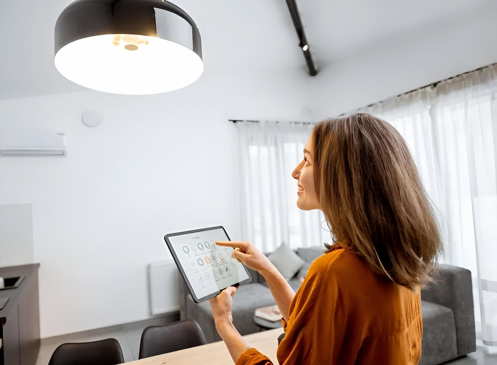 A Woman is Using a Tablet in a Living Room — Adept Security In Thirroul, NSW