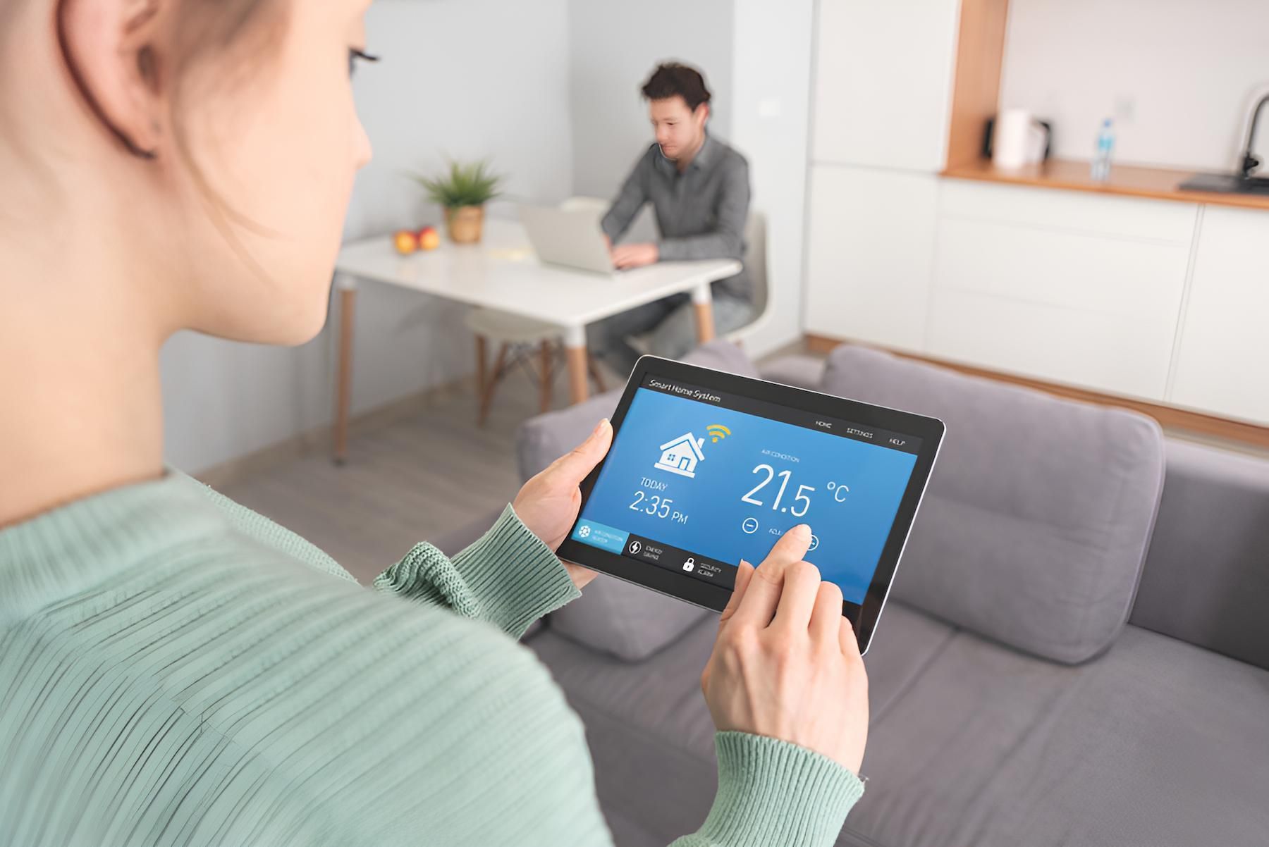 A Woman is Holding a Tablet in Her Hand in a Living Room — Adept Security In Thirroul, NSW