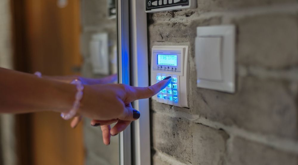 A Woman is Pressing a Button on a Security System — Adept Security Kiama, NSW