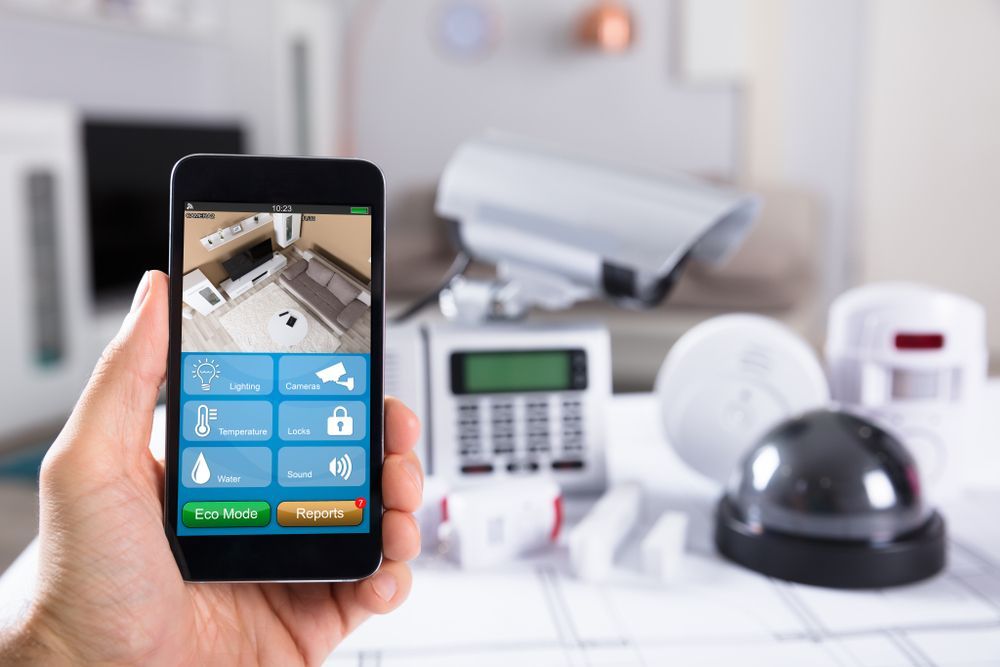 A Person is Holding a Smart Phone With a Security System on It — Adept Security In Oak Flats, NSW
