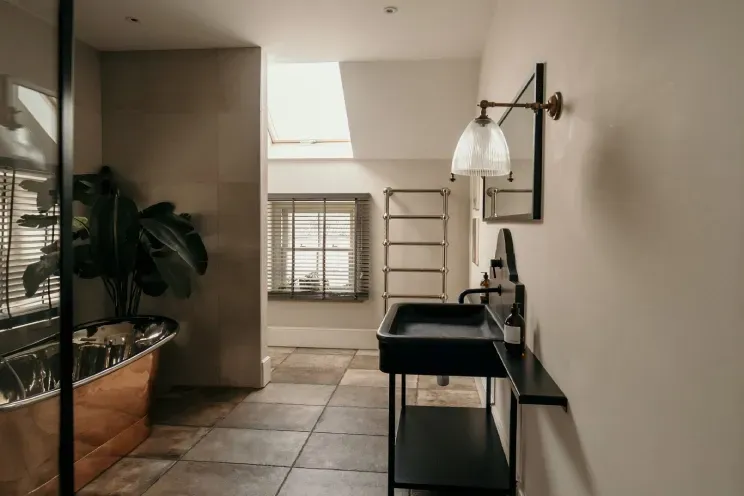 A bathroom with a sink , mirror , tub and window.