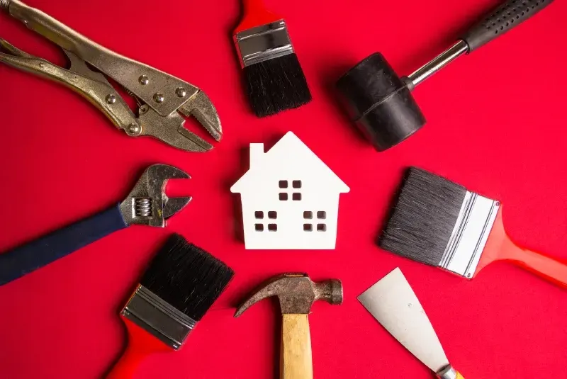 A white house is surrounded by tools on a red background.