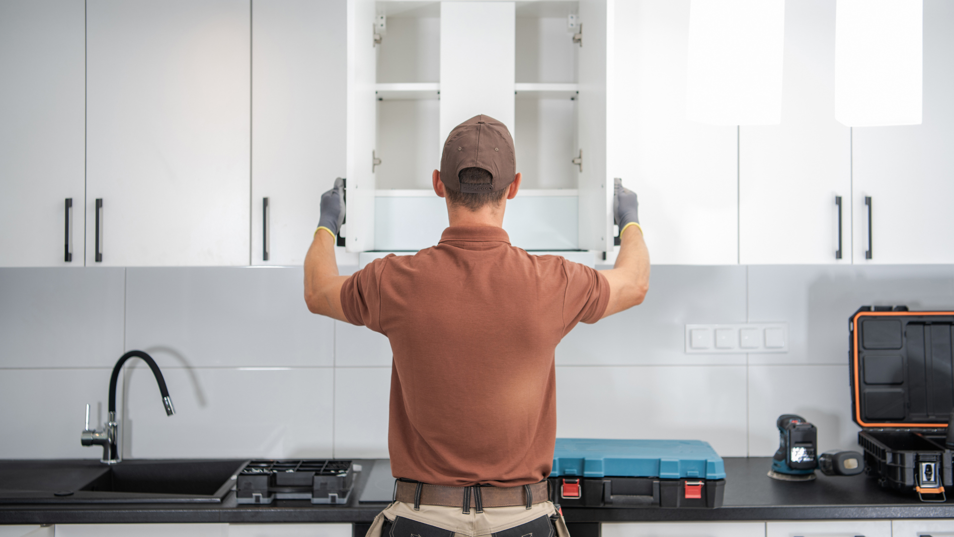 A man is installing cabinets in a kitchen.