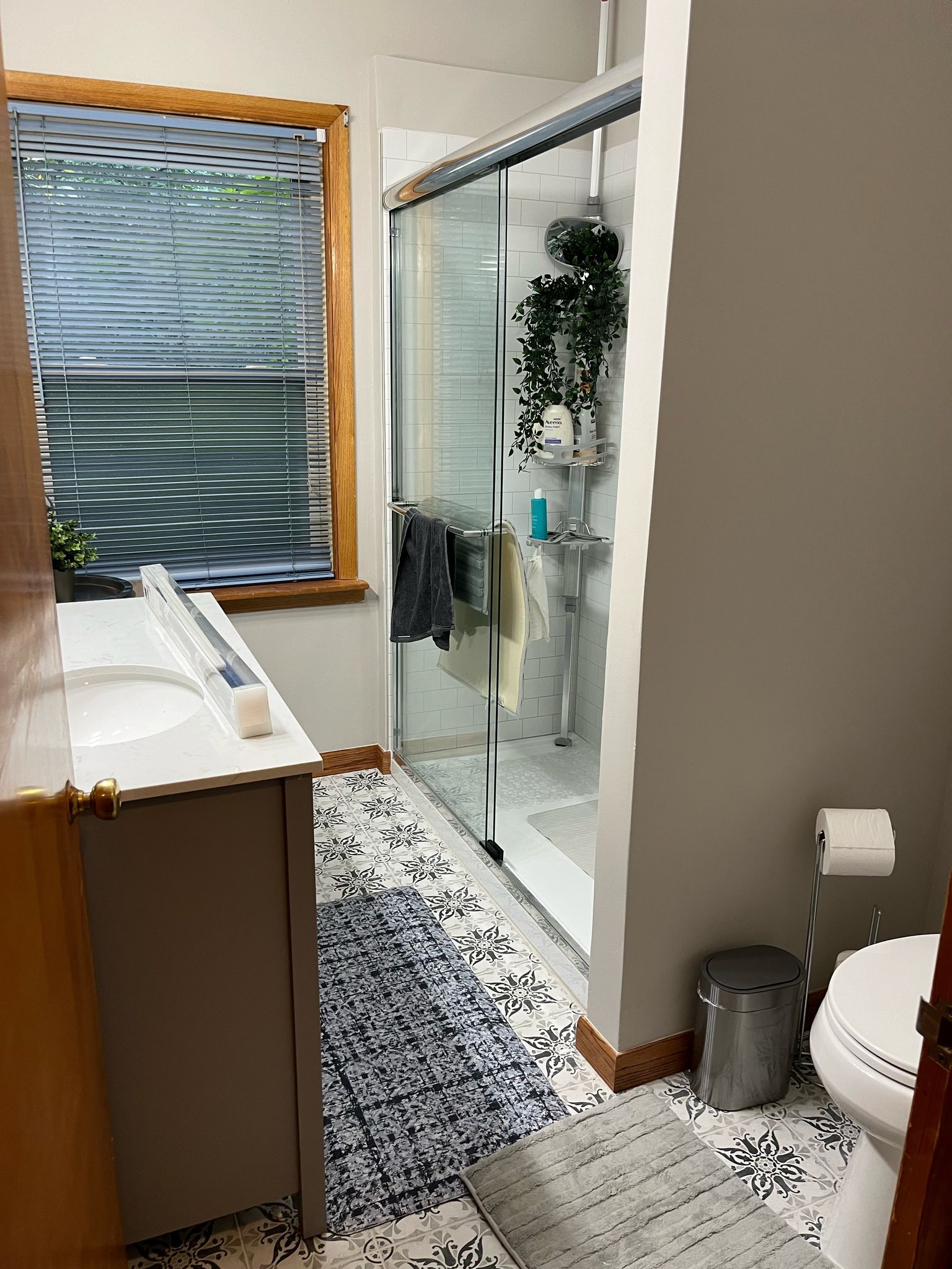 A bathroom with a sink , toilet , shower and window.