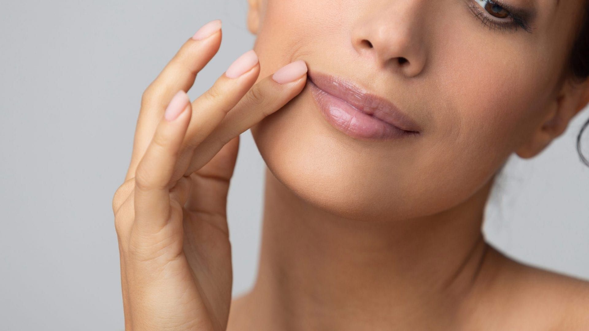 A close up of a woman 's face with her hand on her lips.