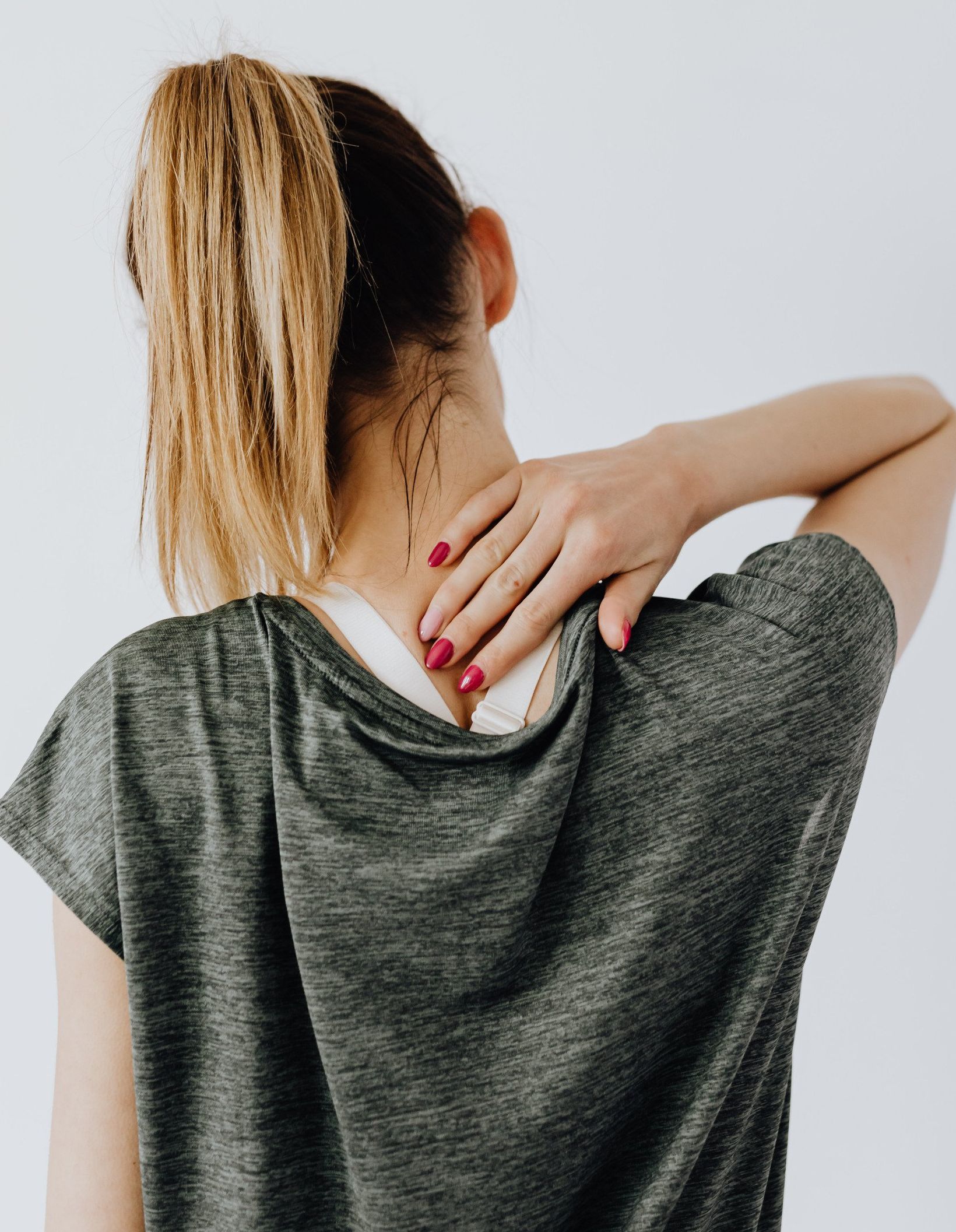 A woman is holding her neck because she has neck aches.