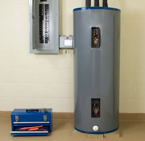 A tall gray water heater is sitting in a room next to a wall.