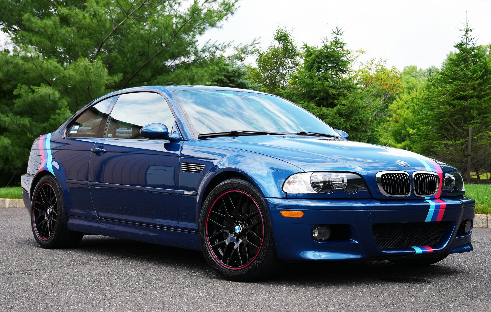 A blue bmw m3 is parked on the side of the road.