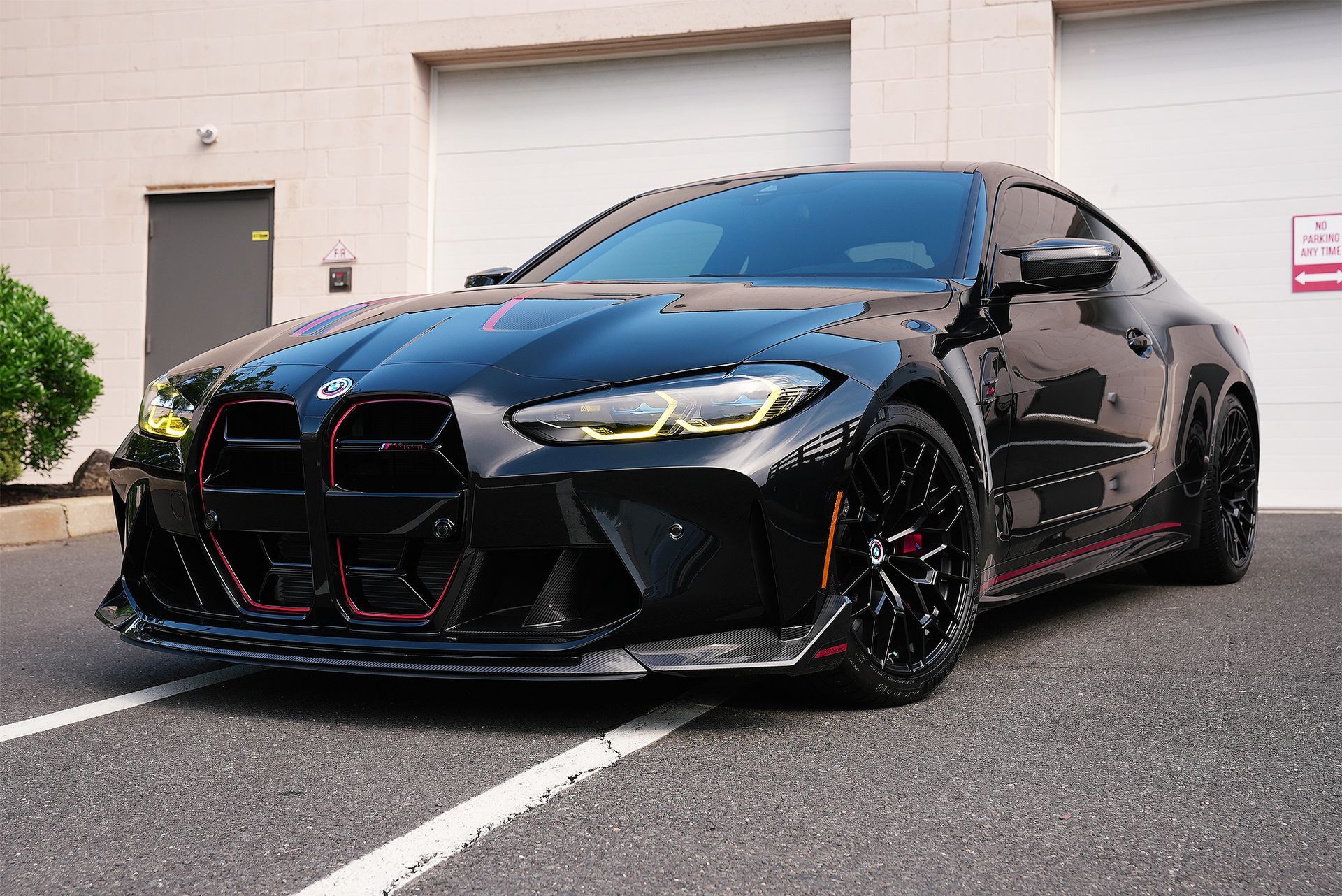 Black sports car parked outside a building, front view with red accents and tinted windows