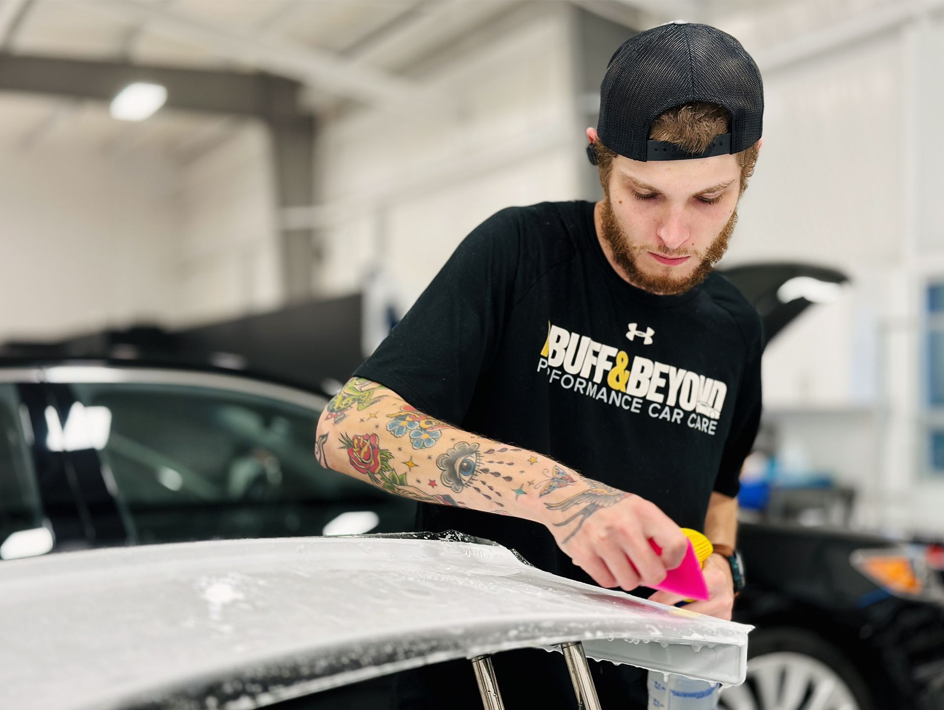 a ma wearing a cap applying ppf on a car