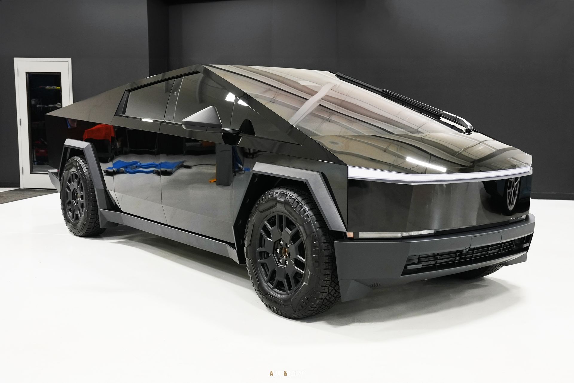 A black tesla cybertruck is parked in a garage.