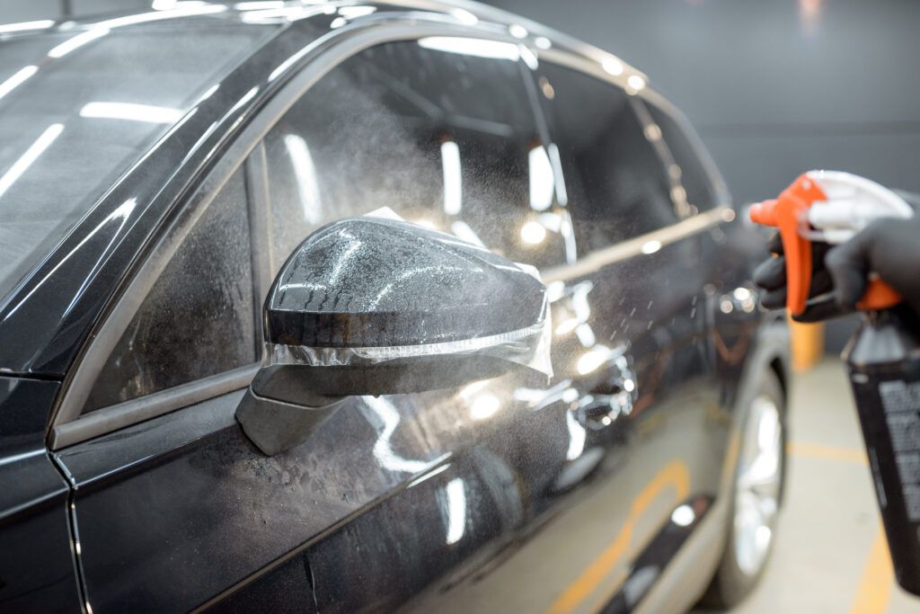 A person is spraying a car with a spray bottle.
