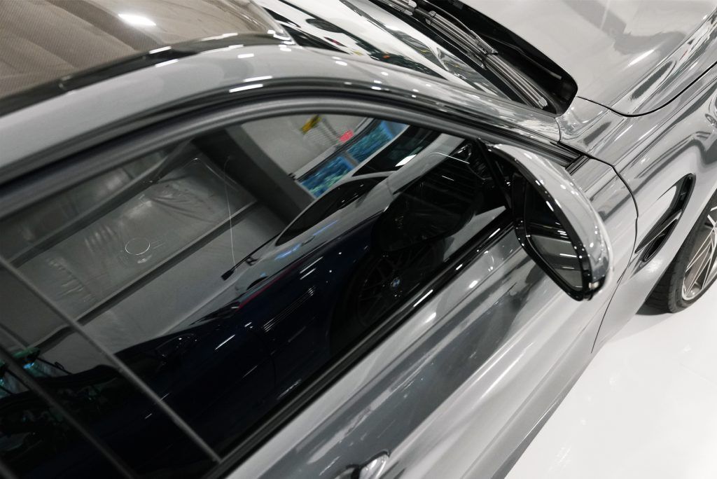 A silver car with black windows is parked in a garage.