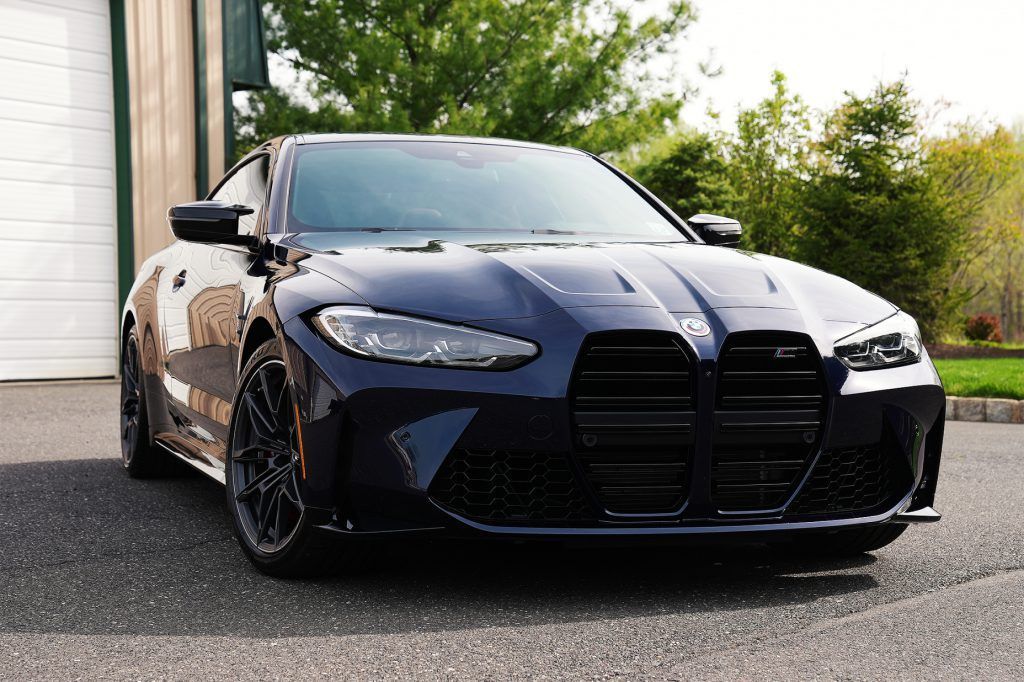 A black bmw m4 is parked in front of a garage.