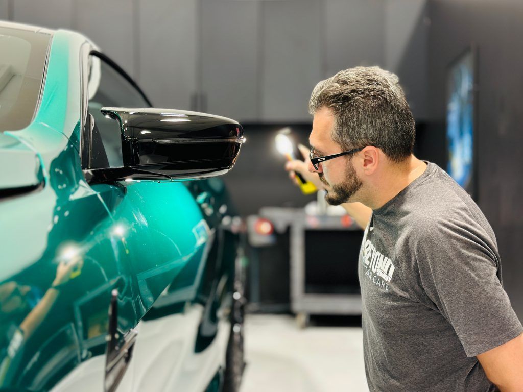 A man is looking at a green car in a garage.