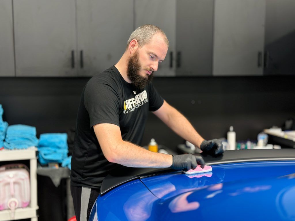 A man is polishing a blue car in a garage.