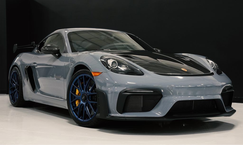 A gray porsche 911 gt3 rs is parked in a showroom.