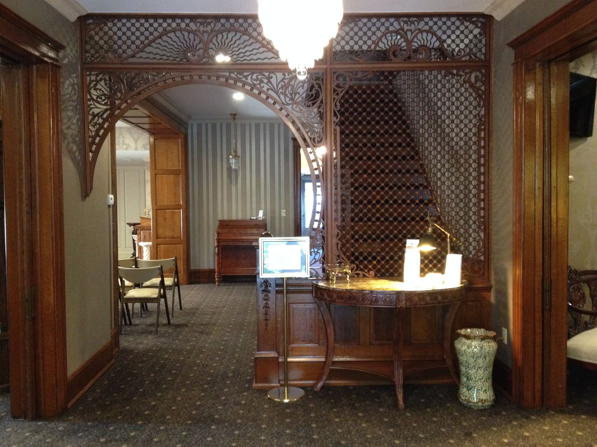 Hotel room with carved wooden partitions, desk lamp, and upholstered chairs in a carpeted interior