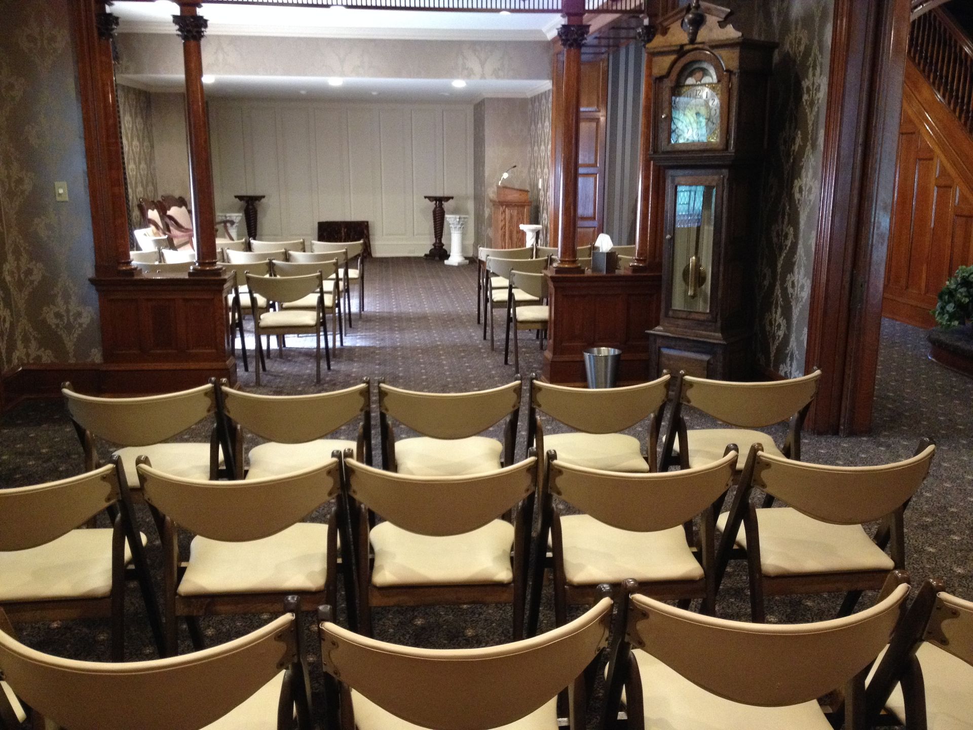 Elegant dining room with set tables and rows of chairs facing a stage-like front area