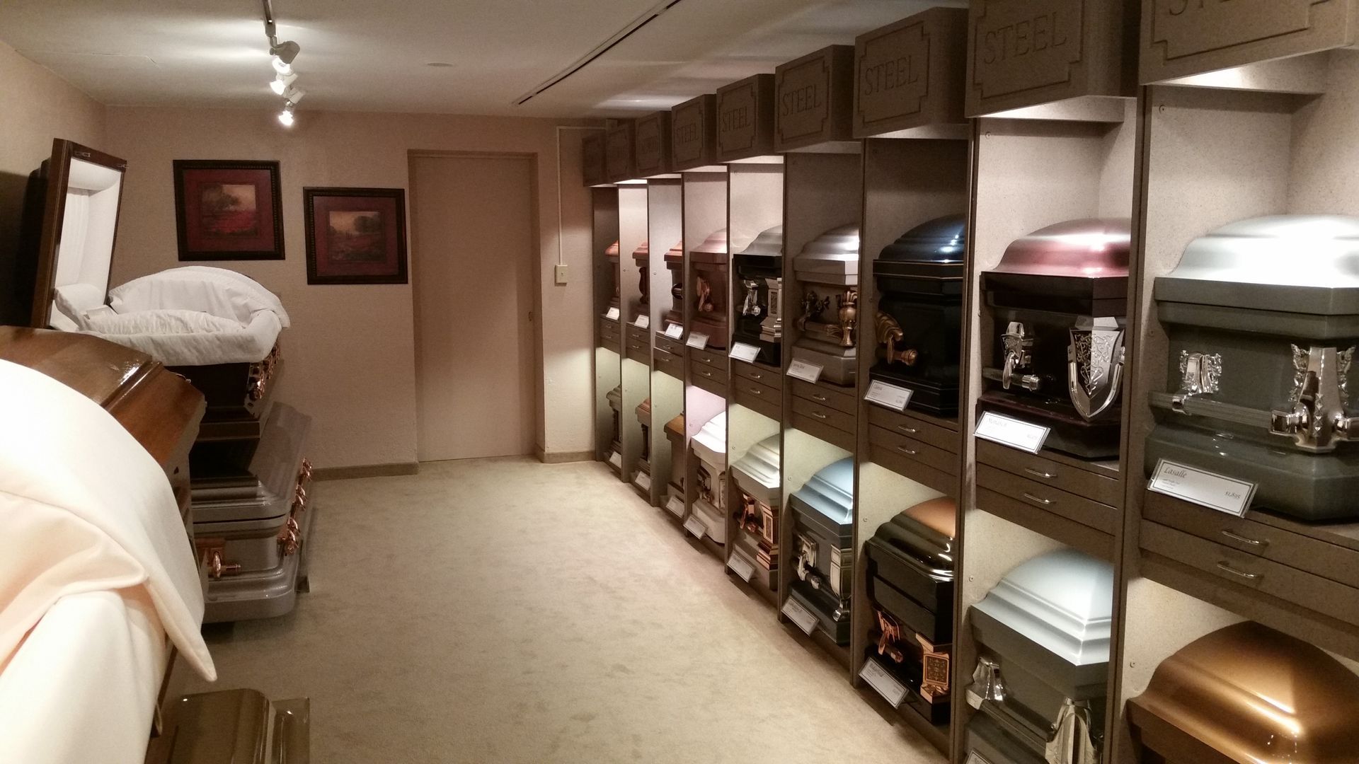Long room with rows of funeral urns or caskets displayed on shelves along the right wall.