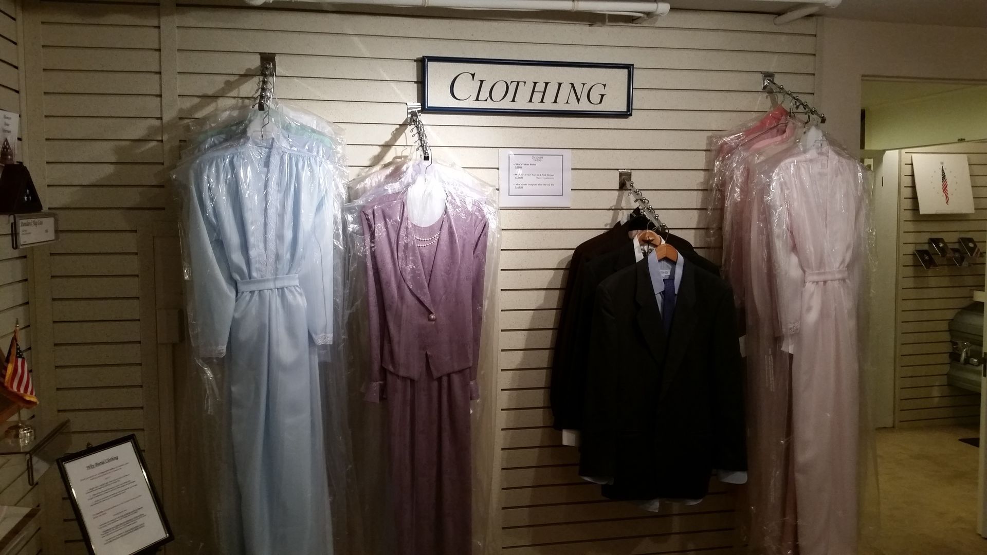 Clothing display with hanging dresses and suits on a slatwall in a store interior