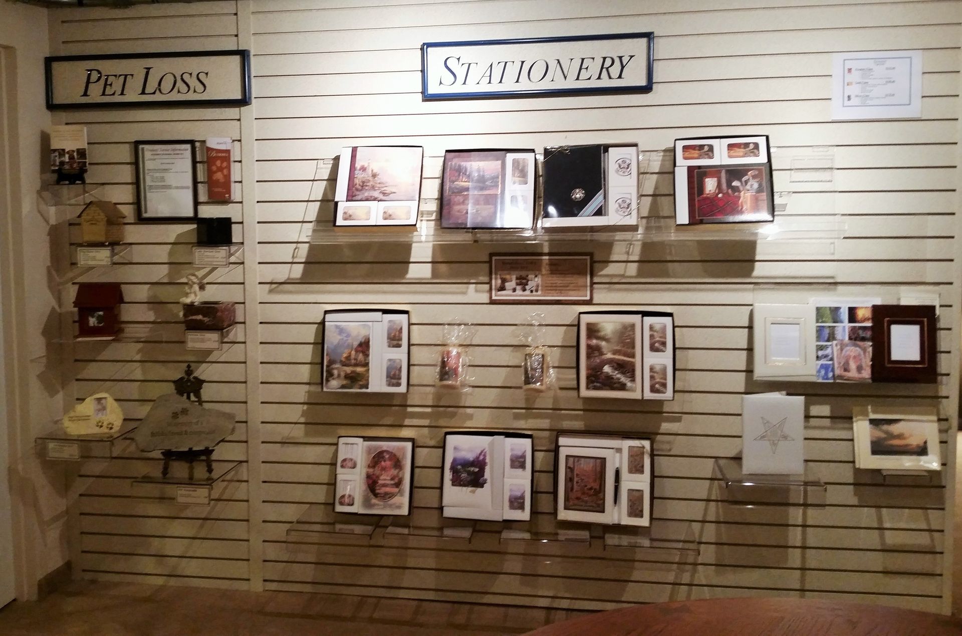 Display of pet loss and stationery cards on a slat wall in a shop or gallery.
