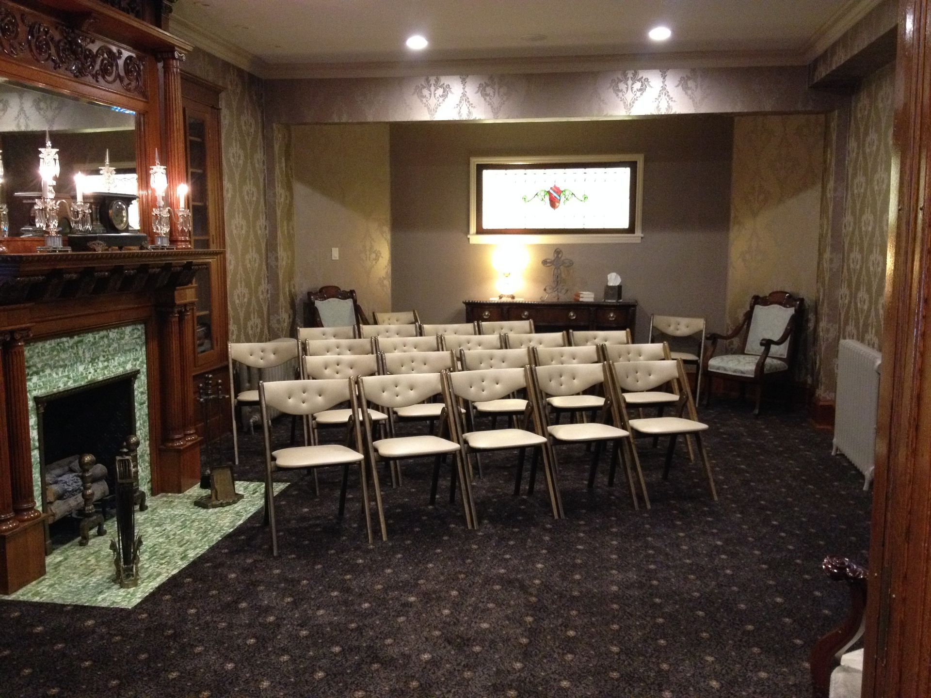 Small conference room with rows of beige chairs, fireplace, and framed art on the wall.