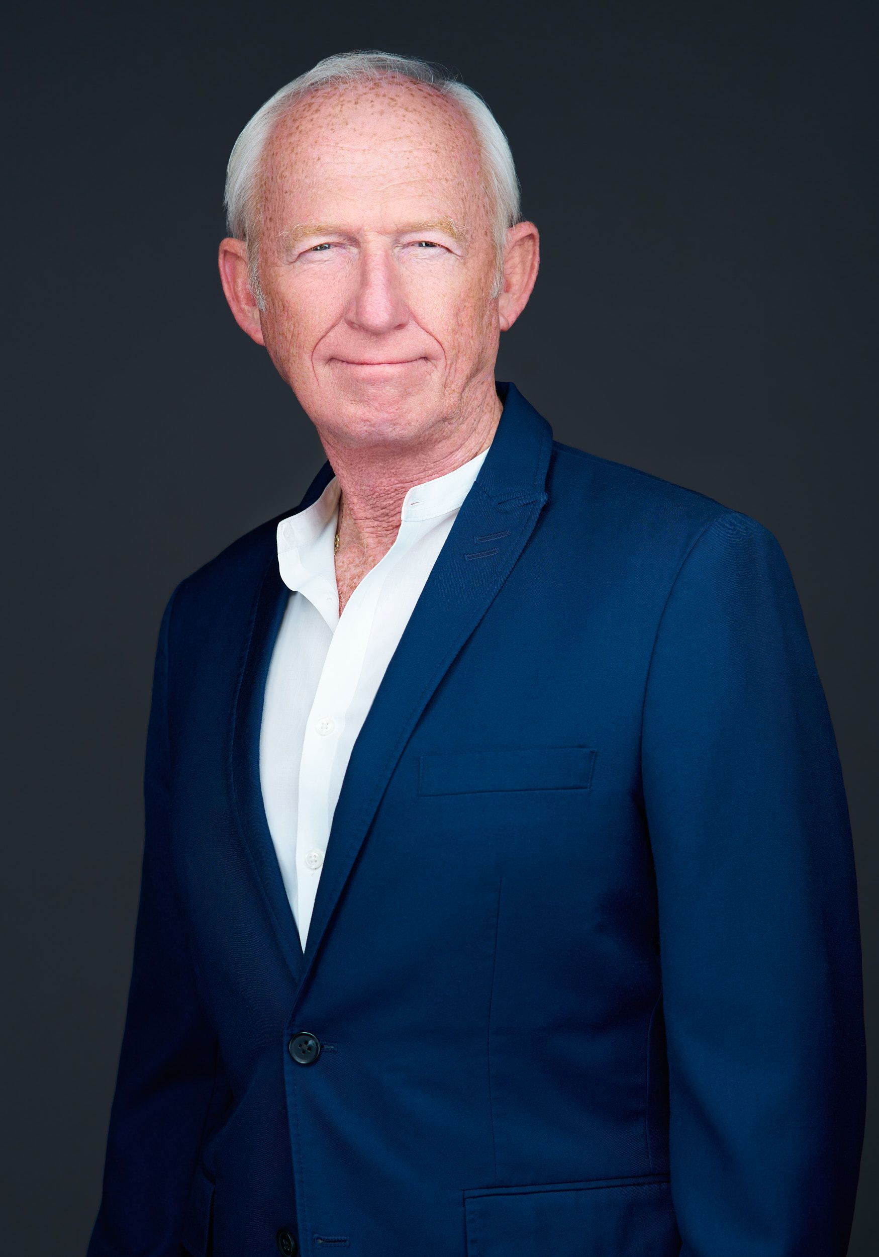 A man in a suit and tie is standing with his hands in his pockets.