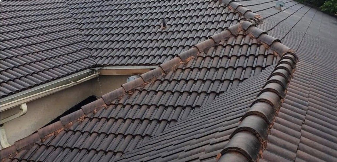 Brown tiled roof with a central ridge line and a broken section near the peak