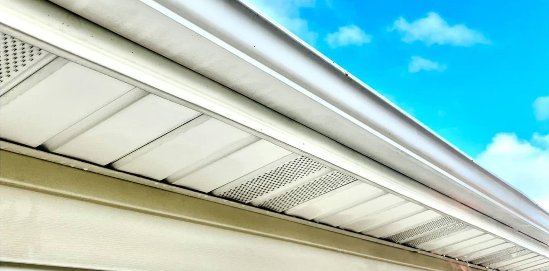 White house roof eaves with vents against a bright blue sky