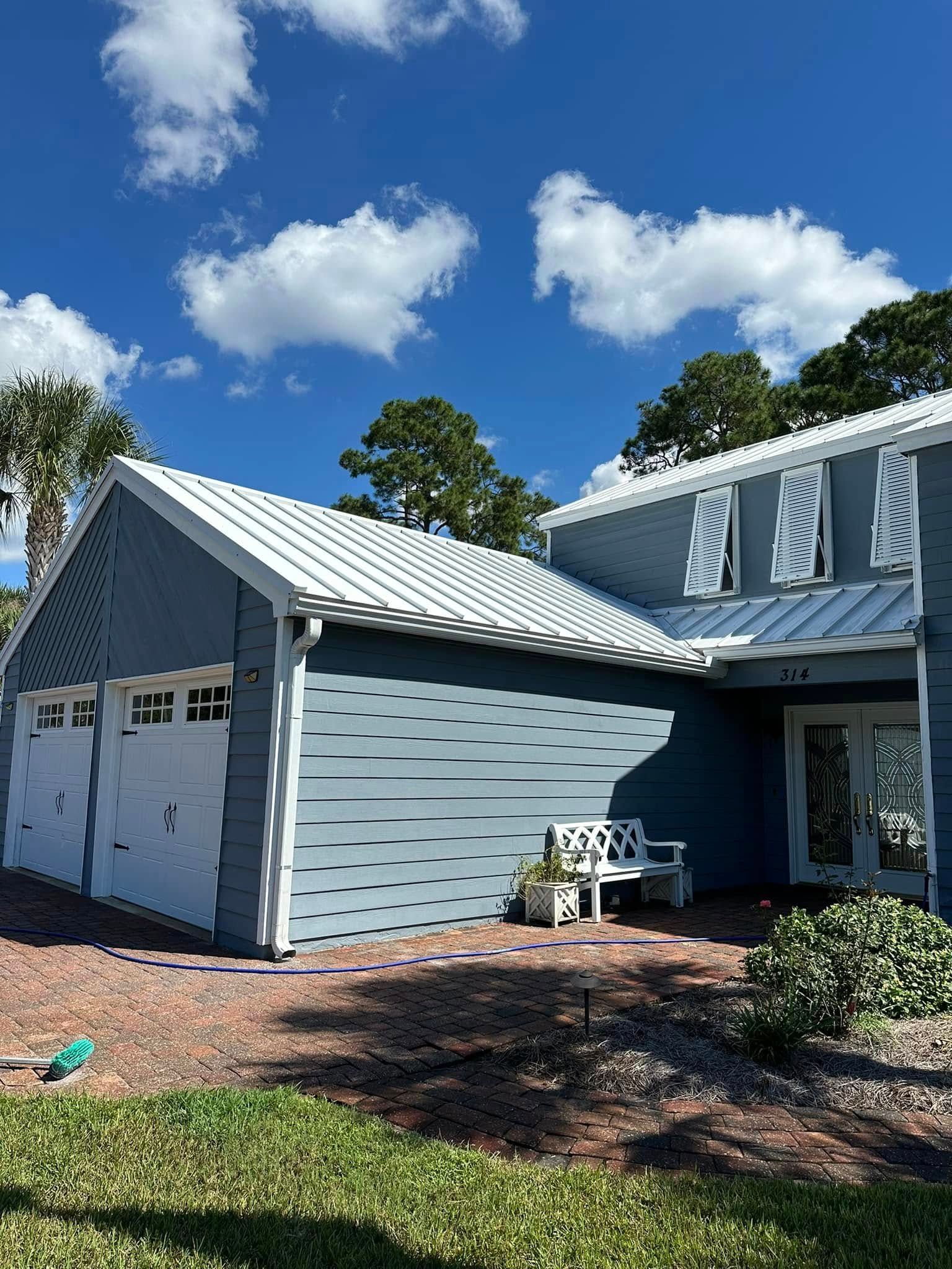 Light blue house with white trim, a two-car garage, and a front porch under a bright blue sky.