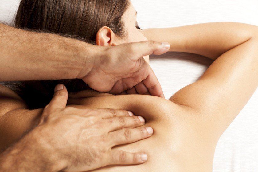 A man is giving a woman a massage on her back.