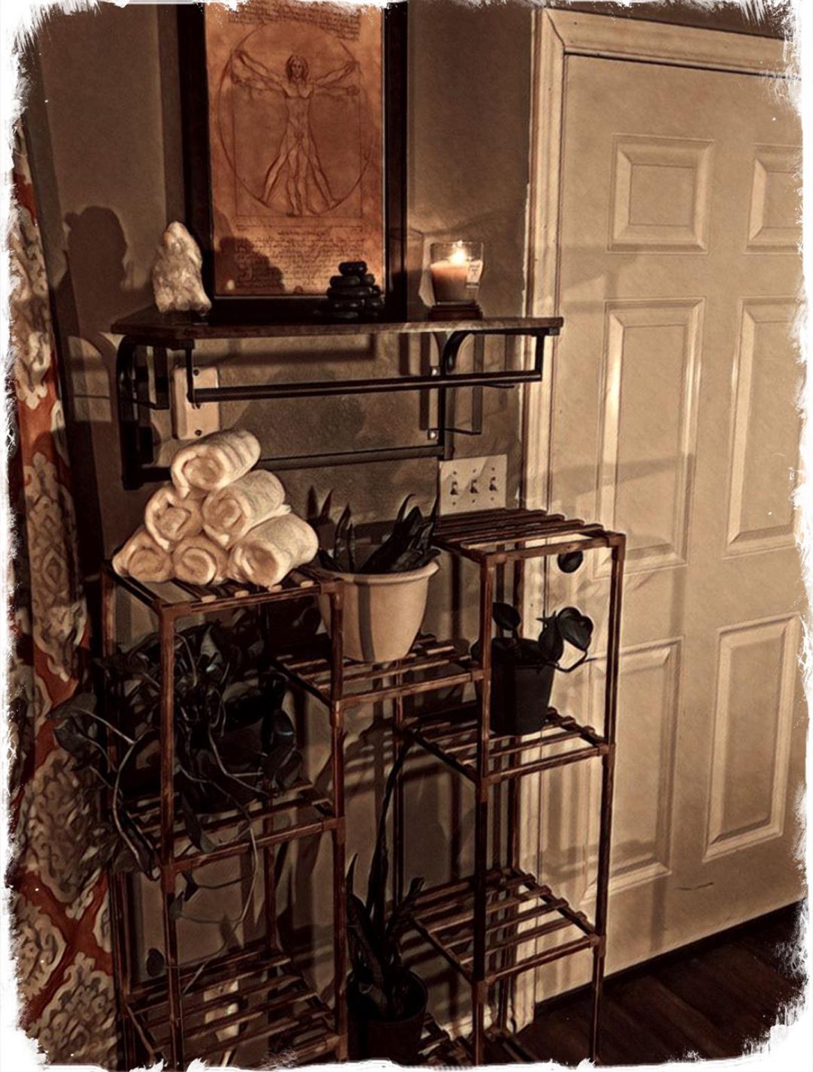 Rustic bathroom with metal shelving, rolled white towels, candles, and a closed white door