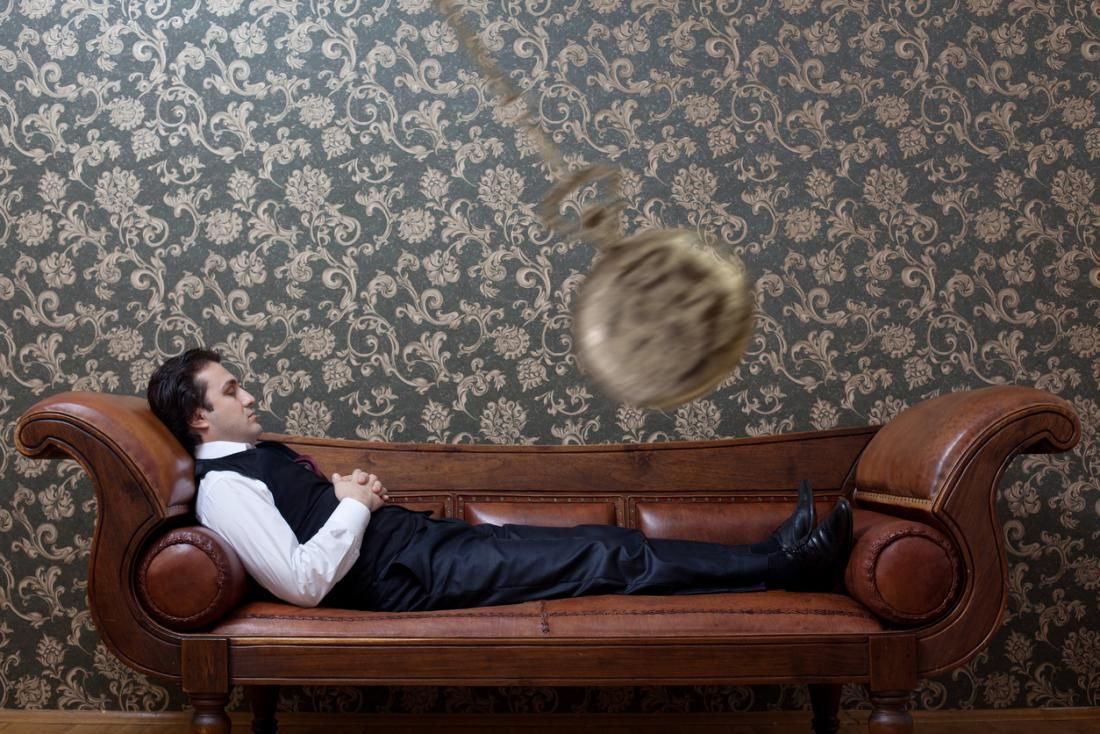 A man is laying on a couch with a pendulum hanging from it.